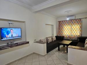 ein Wohnzimmer mit einem Sofa und einem Flachbild-TV in der Unterkunft Résidence Anouar in Tétouan