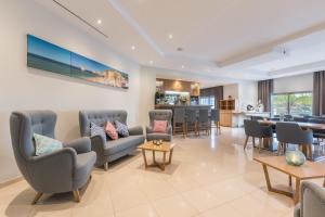 a living room with chairs and tables and a kitchen at Caneiros Luxury House & Suites in Ferragudo