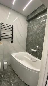 a white bath tub in a bathroom with marble walls at Heaven Apartment Mountain View in Almaty