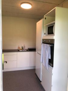 eine Küche mit weißen Schränken und einer Mikrowelle in der Unterkunft Pulzion - Sportshotel in Kolding