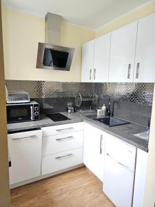 eine Küche mit weißen Schränken und einer Mikrowelle in der Unterkunft Lazur Apartamenty in Świnoujście
