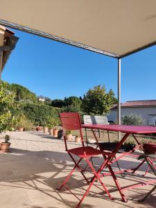 einem roten Tisch und einem Stuhl unter einem Schirm in der Unterkunft LE CHARME DU VENTOUX in Crillon-le-Brave