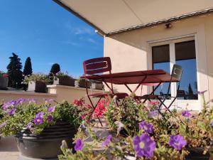 a red table and chairs on a patio with flowers at LE CHARME DU VENTOUX in Crillon-le-Brave