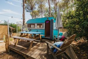 una mesa y sillas en una terraza con una caravana en Vallicella Glamping Resort, en Scarlino