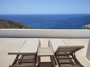 2 bancos sentados en un balcón con vistas al océano en Sifnos "Sofia apartments" sea view, en Faros