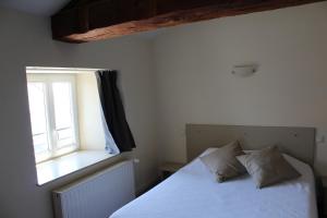 sypialnia z białym łóżkiem i oknem w obiekcie Auberge de la Planèze w mieście Talizat