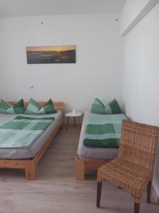 2 Betten in einem Zimmer mit einem Stuhl und einem Tisch in der Unterkunft Ferienwohnung Waldblick mit Balkon in Sebnitz