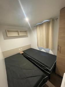 Cette petite chambre comprend un lit et un rideau. dans l'établissement Particulier loue mobil-home dans le parc siblu, à Saint-Brévin-les-Pins