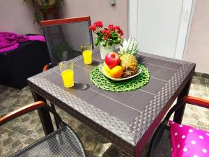 una mesa con un bol de fruta y dos vasos de zumo de naranja en Kuća Lilla, en Loborika