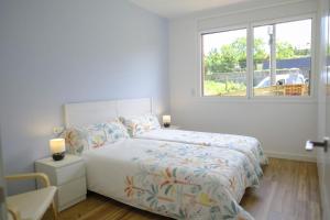 a white bedroom with a bed and a window at La Paserina de Pría in Llames de Pría