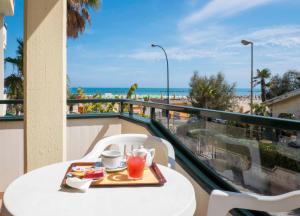 een dienblad met eten op een tafel op een balkon met uitzicht op het strand bij Hotel Roma Sul Mare in Roseto degli Abruzzi