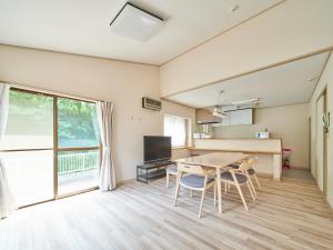 um quarto com uma mesa e cadeiras e uma televisão em Villa Miura Beach -ヴィラ三浦海岸- em Miura