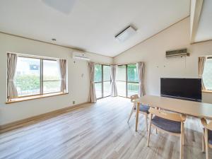 een kamer met een tafel, stoelen en ramen bij Villa Miura Beach -ヴィラ三浦海岸- in Miura