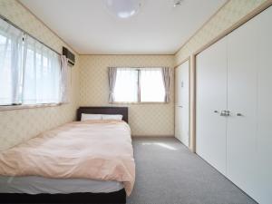 a bedroom with a bed and two windows at Villa Miura Beach -ヴィラ三浦海岸- in Miura