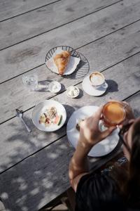 a person holding a cup of coffee and plates of food at Holzhotel Forsthofalm in Leogang