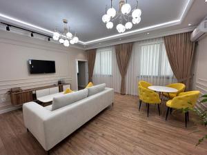 sala de estar con sofá blanco y sillas amarillas en Home Apartment Complex, en Shymkent