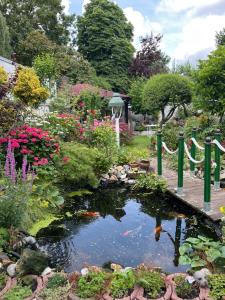 einen Garten mit einem Teich mit Blumen und einer Brücke in der Unterkunft Appartement am Teich in Krefeld