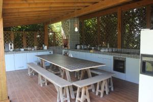 an outdoor kitchen with a table and benches at Quintinha do Poceirão in Águas de Moura