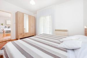 1 dormitorio blanco con 1 cama grande con almohadas blancas en Apartments Magnolia en Rovinj