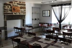 une salle à manger avec des tables, des chaises et une cheminée dans l'établissement Auberge de la Planèze, à Talizat