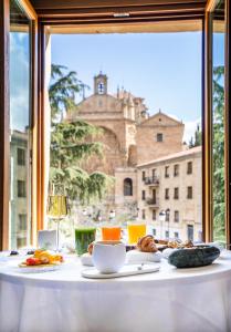 a table with food and a view of a castle at Grand Hotel Don Gregorio in Salamanca