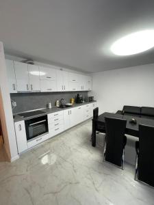 uma cozinha com armários brancos e uma mesa e cadeiras em Regim Hotelier DEVA, str. Mihai Viteazu, bl. RESIDENCE !!! em Deva