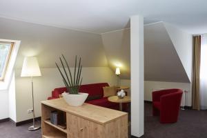 a living room with a red couch and a table at Sunday Hotel Friedrichroda & SPA in Friedrichroda +47 photos