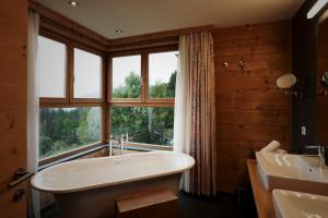 łazienka z wanną i dużym oknem w obiekcie Holzhotel Forsthofalm w mieście Leogang