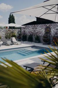 a swimming pool with chairs and umbrellas on a patio at VILA MILAGO l Baile Felix l ORADEA l Jacuzzi & Sauna in Baile Felix