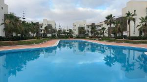 a large pool with blue water in front of buildings at Perla à 200 m de la plage in Saïdia