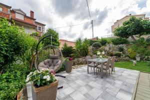 a patio with a table and chairs in a garden at Studio apartment with garden at Split suburbs in Stobreč