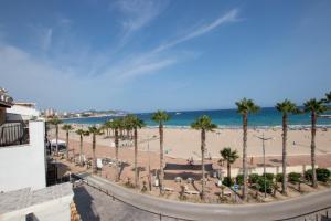 a view of a beach with palm trees and the ocean at HAPPYVILA Fisher House in Villajoyosa