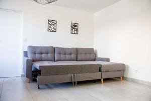 un sofá en una habitación con una pared blanca en Renovated T6 house with garden near transport, en Villenave-dʼOrnon