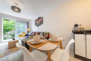 eine Küche und ein Wohnzimmer mit einem Tisch und Stühlen in der Unterkunft Ashview 6 - Heathrow - Windsor - Free Parking in Staines upon Thames