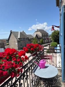 balcón con flores rojas, mesa y sillas en Auberge de la Planèze en Talizat