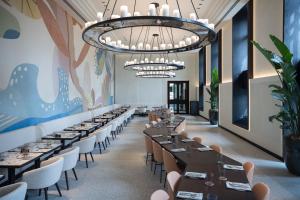 a dining room with tables and chairs and a large chandelier at Almanac Palais Vienna in Vienna