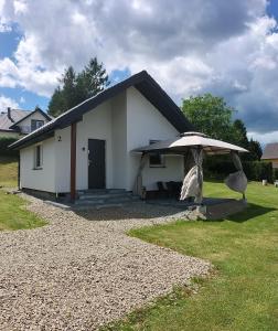 un pequeño edificio blanco con un paraguas en un patio en Bieszczadzki Orzeł en Berezka