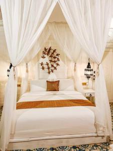 a bedroom with a white canopy bed with curtains at Mytongos Private Villa in Nusa Lembongan