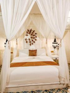 a bedroom with a white canopy bed with curtains at Mytongos Private Villa in Nusa Lembongan +15 photos