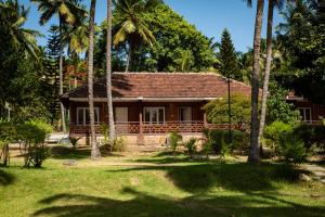 a house with palm trees in front of it at Ibex River Resort, Pollachi in Coimbatore