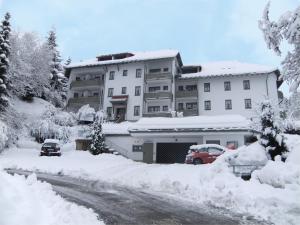 a snow covered building with cars parked in front of it at Fewo 12 - Residenz Schauinsland, E-Ladestation, Todtnauberg, Feldberg in Todtnauberg