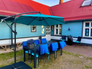 einem Tisch mit blauen Stühlen und einem Regenschirm vor einem Haus in der Unterkunft Villa Blue Heaven Pärnu in Pärnu