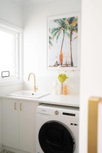 cocina blanca con lavadora y fregadero en Luxury hideaway holiday unit in CBD, en Mount Gambier
