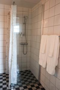 uma casa de banho com um chuveiro e toalhas brancas em Ludvigsdal Semesterboende em Ystad