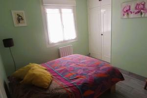 een slaapkamer met een bed met een kleurrijk dekbed en een raam bij Maison tout confort avec jardin in Cayeux-sur-Mer