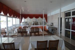 a dining room with tables and chairs and a kitchen at Yasmin Hotel in Ayvalık