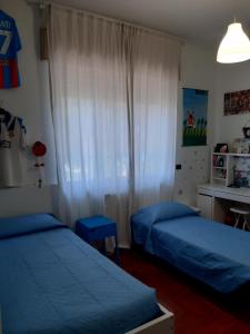 1 Schlafzimmer mit 2 Betten mit blauer Bettwäsche und einem Fenster in der Unterkunft Dilly Home Holiday-Casa vacanze in Aci Castello