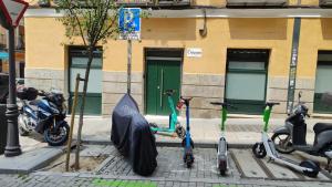 un grupo de scooters estacionados en una calle con un paraguas en Malasaña Dreams S,L en Madrid