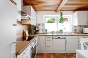 a kitchen with white cabinets and a wooden ceiling at Urlaub an der Ostsee in Steinbergkirche