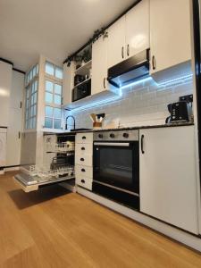 uma cozinha com armários brancos e um forno preto em Reformado a estrenar a 1 minuto estación Tren-Bus Vialia Vigo em Vigo